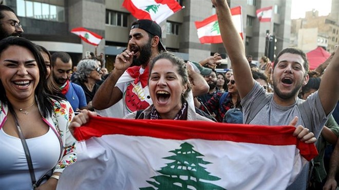 Protesters celebrate the resignation of Prime Minister Saad Hariri in Beirut [Patrick Baz/AFP]